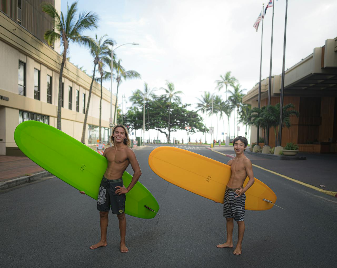 Two young surfers holding surfboards on a city street, ready for adventure.